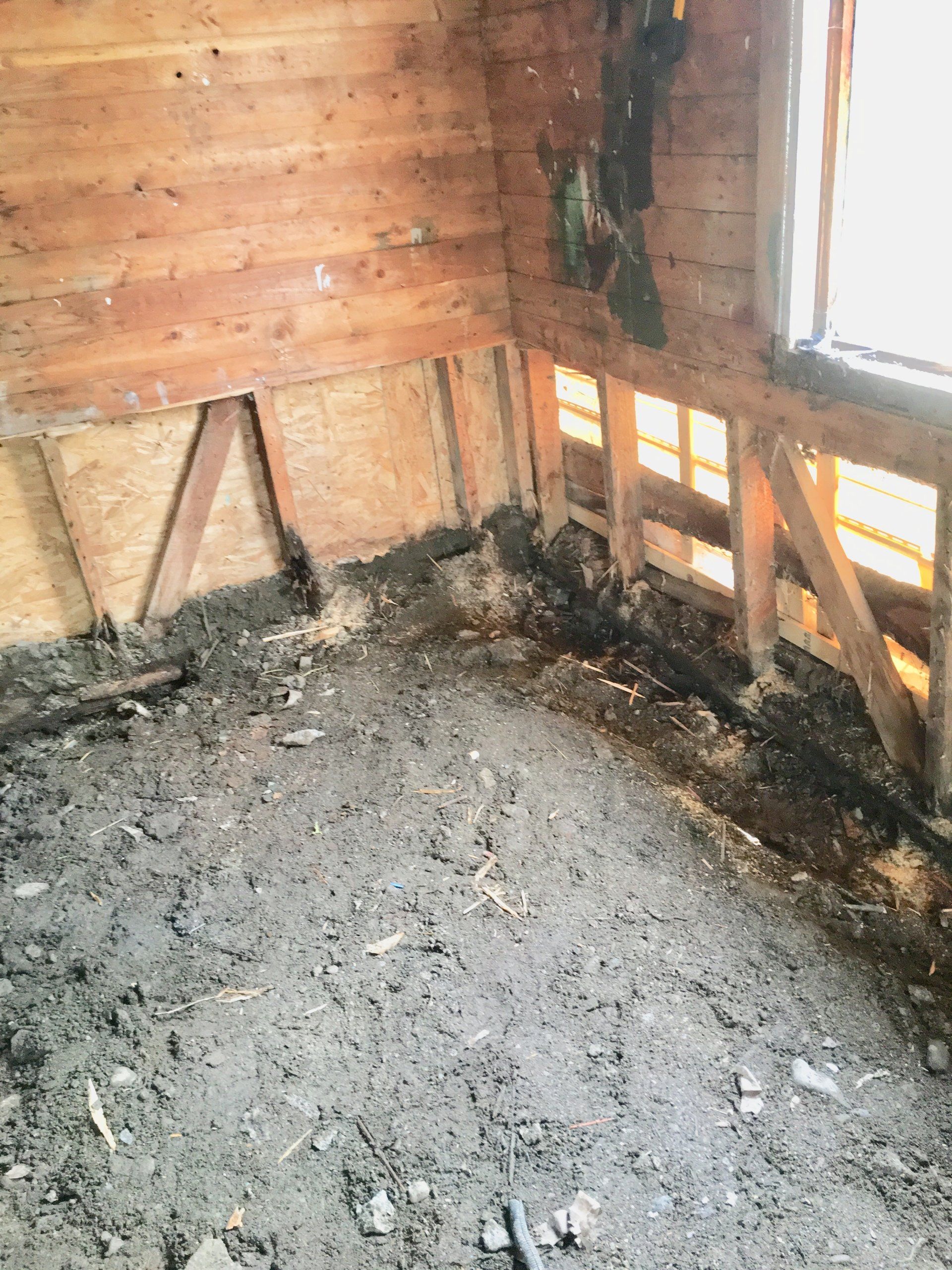 Une pièce avec beaucoup de saleté sur le sol et une fenêtre.