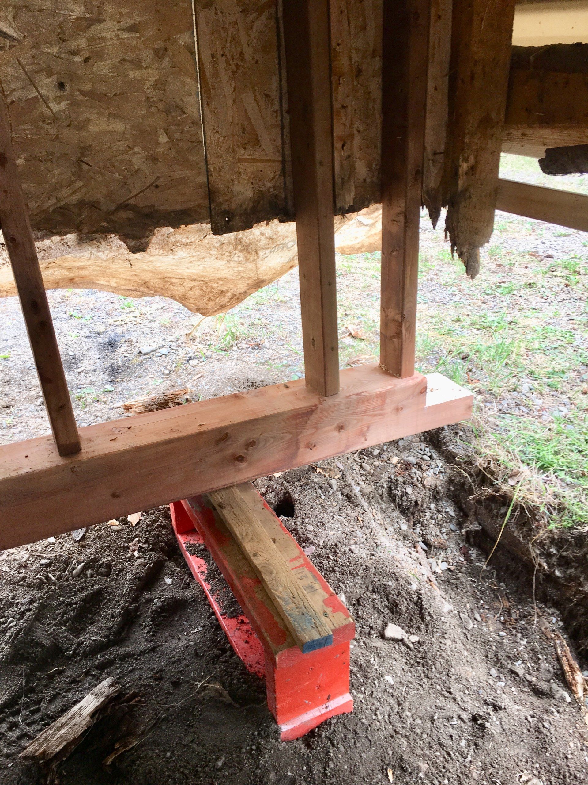 Une échelle rouge est posée sur le sol à côté d'une structure en bois.
