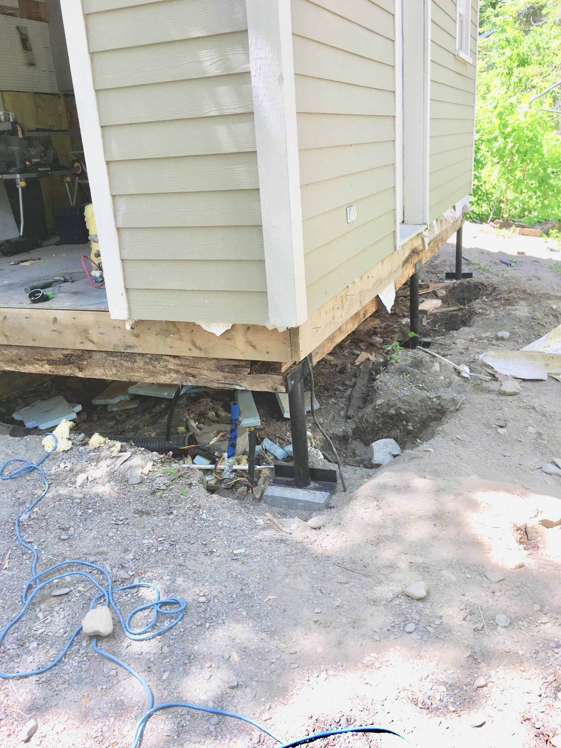 Une maison est en train d'être construite sur pilotis dans la terre.