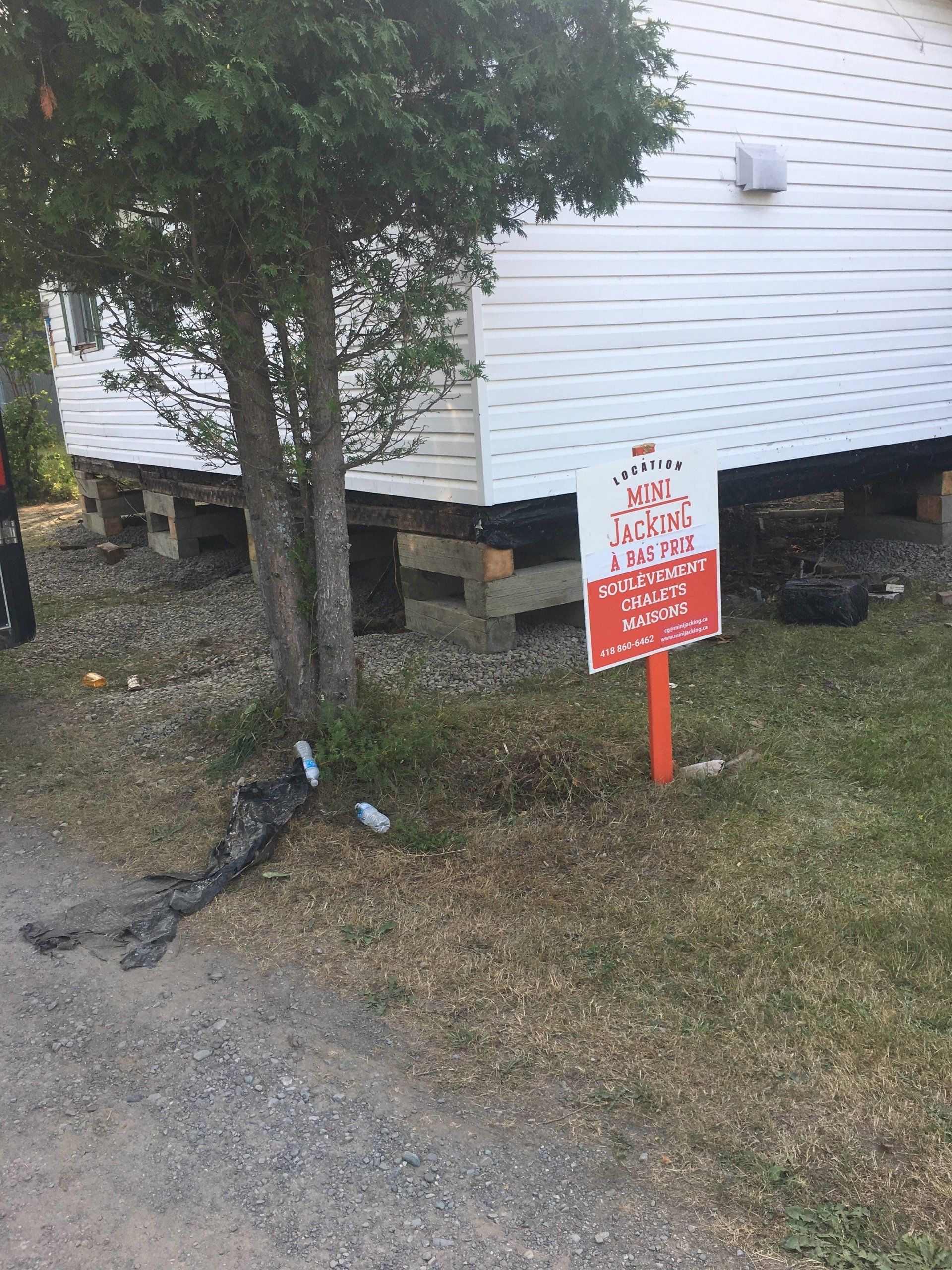 Un panneau rouge et blanc est placé devant une maison blanche.