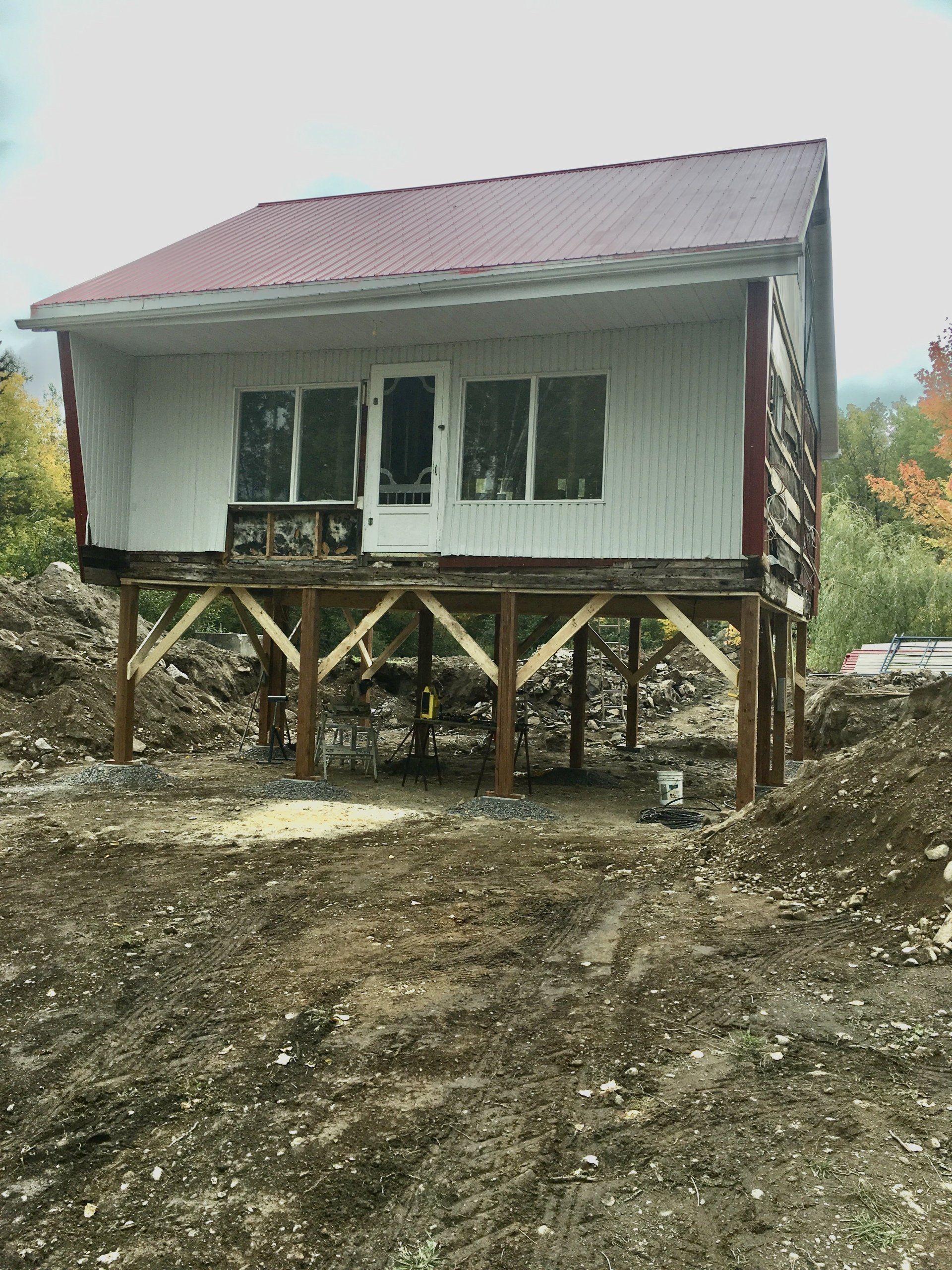 Une petite maison est posée sur des pilotis au milieu d'un champ de terre.