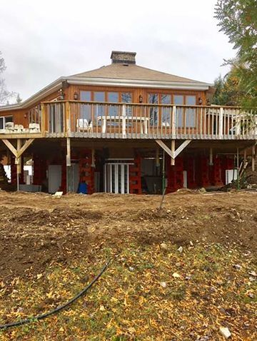 Une grande maison avec une grande terrasse est située au sommet d'un champ de terre.