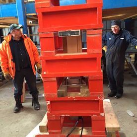 Deux hommes se tiennent à côté d'une pile de blocs rouges.