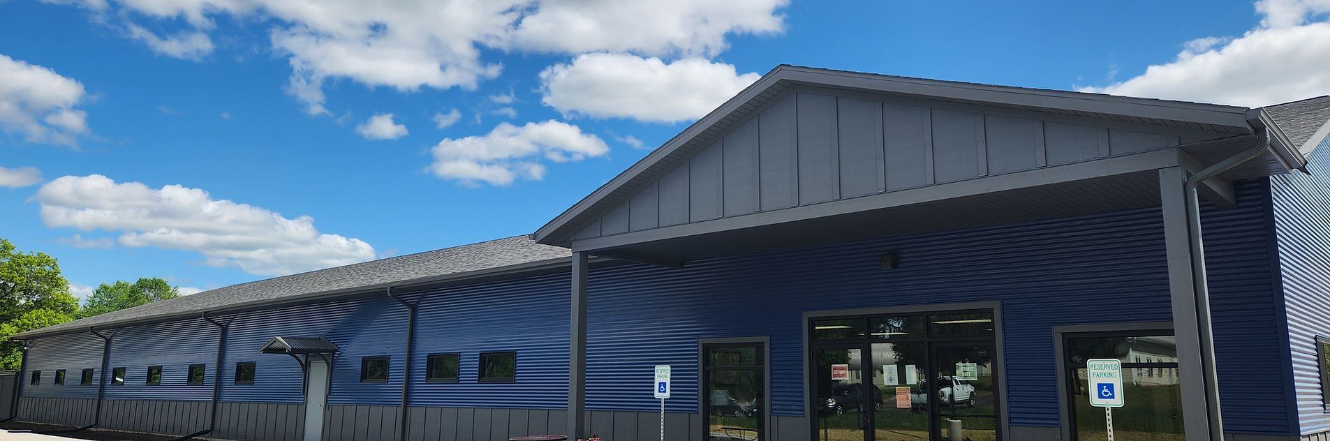 Blue building with a dark gray roof against a blue sky with clouds. Blue building with a dark gray roof against a blue sky with clouds.