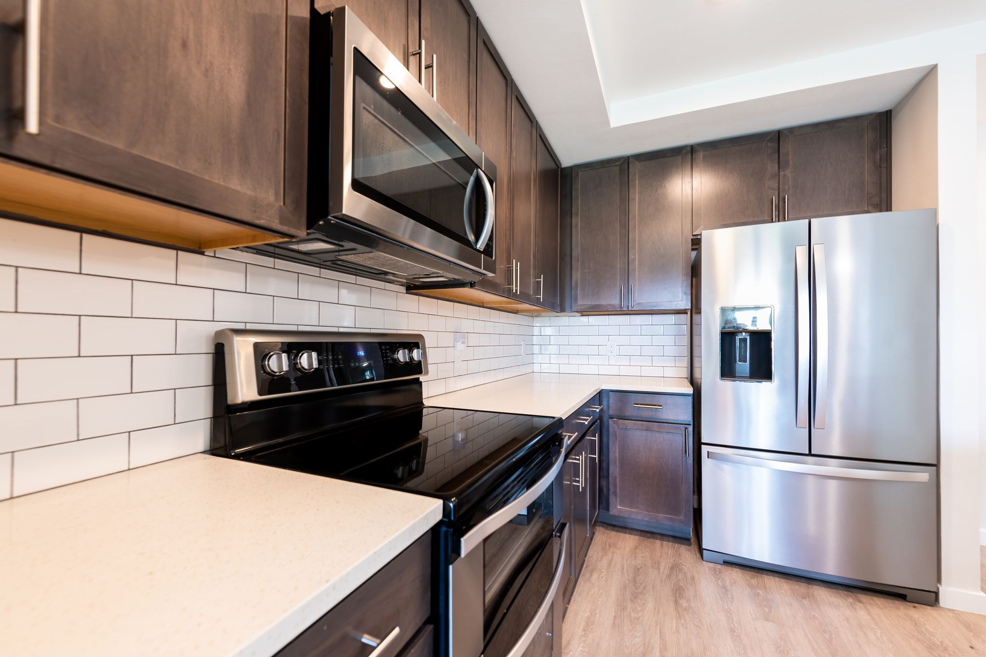 Modern kitchen with stainless steel appliances, white subway tile backsplash, and dark wood cabinets