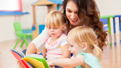A woman is reading a book to two little girls.