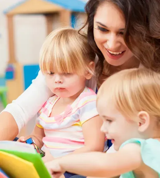 A woman is reading a book to two little girls.