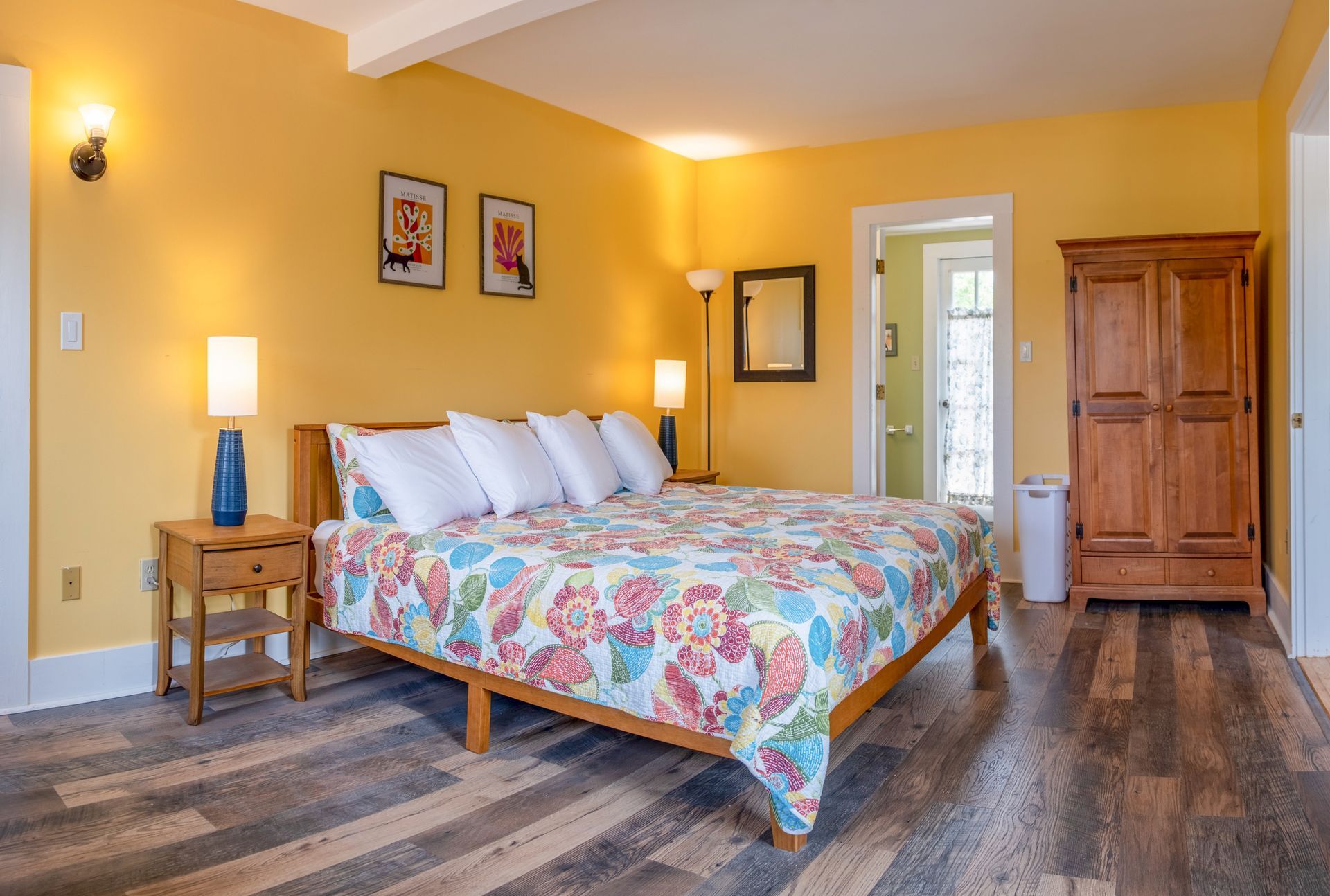 A bedroom with a large bed and a wooden floor.