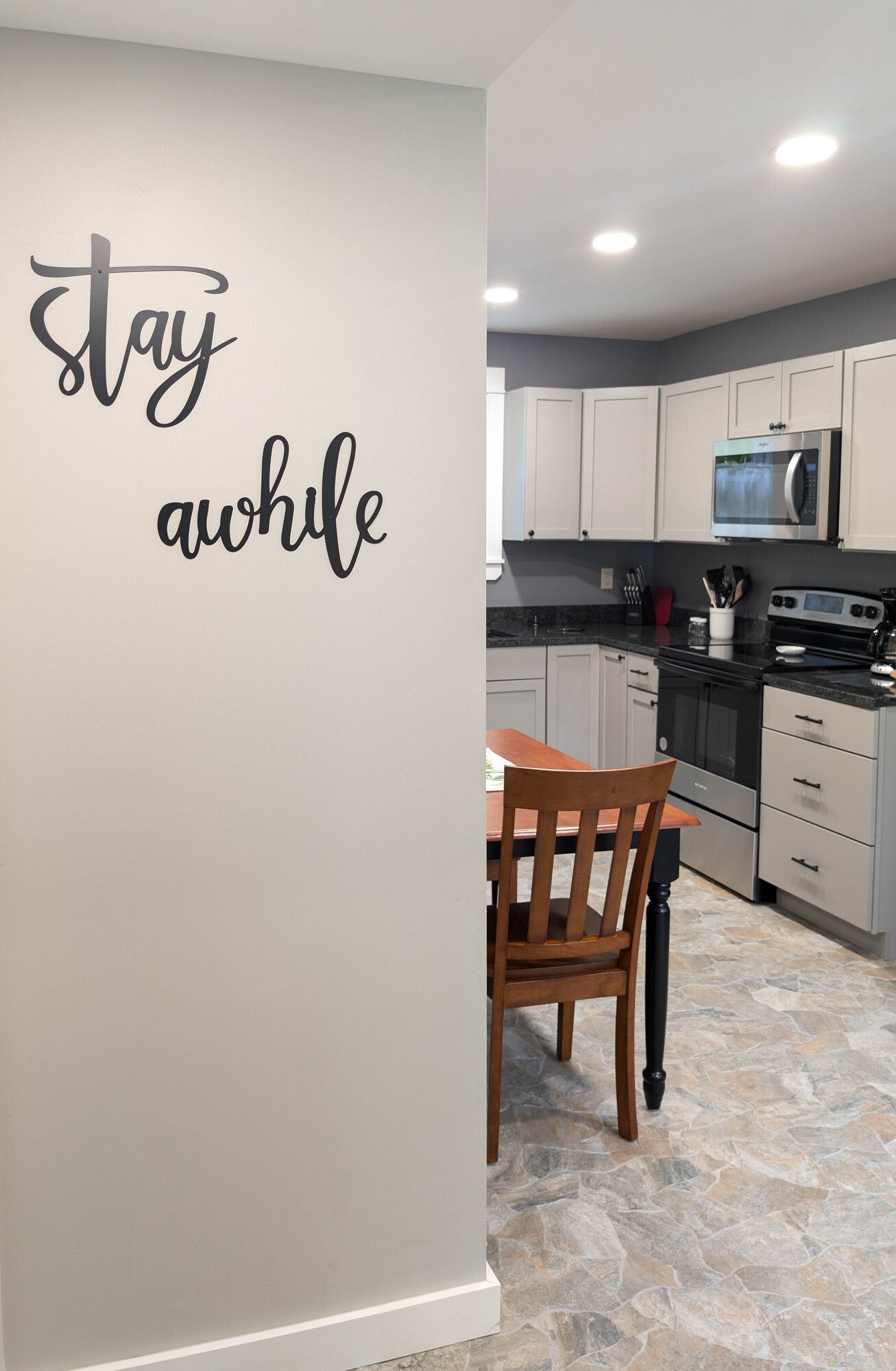 A kitchen with a sign on the wall that says `` stay awhile ''