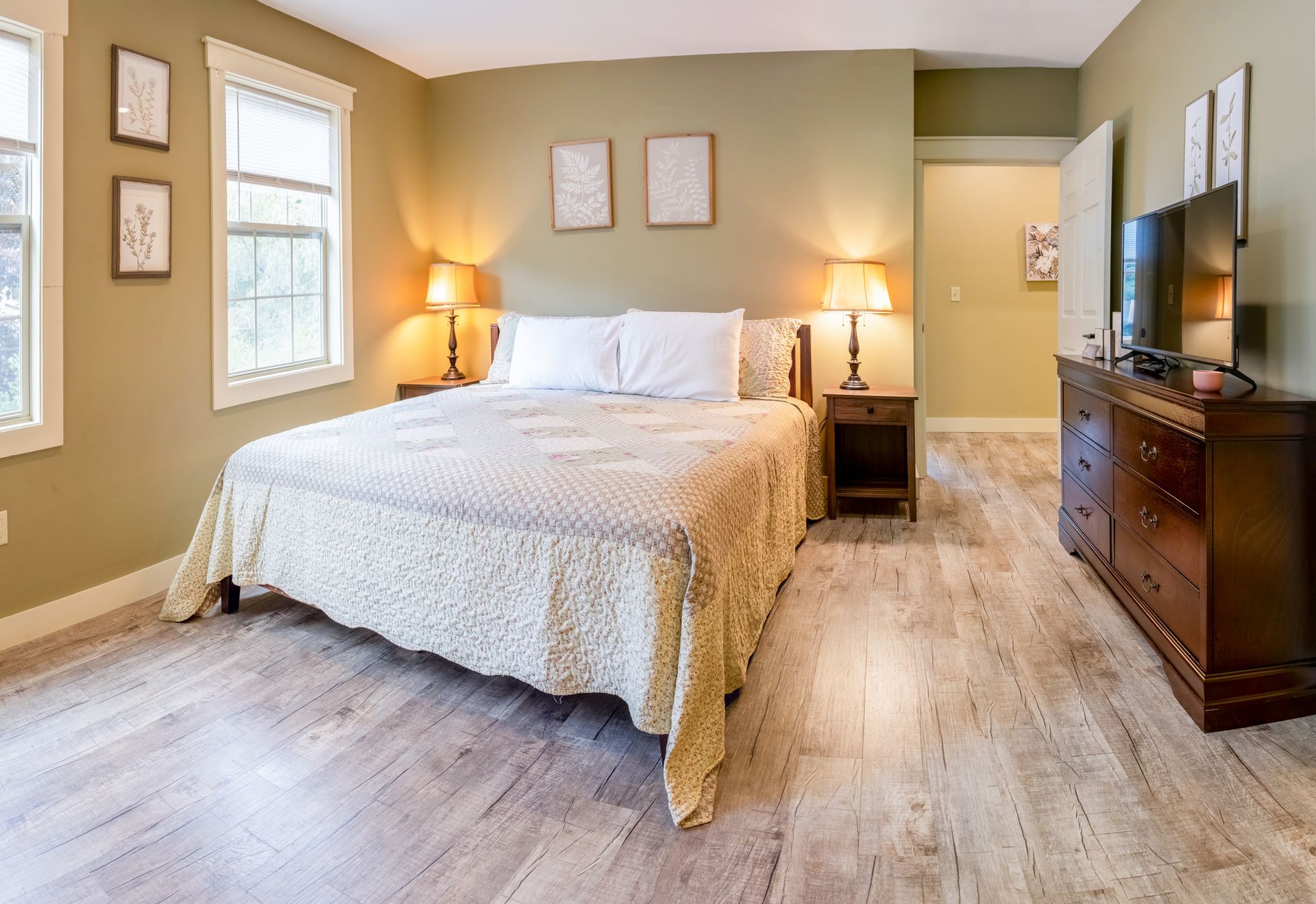 A bedroom with a king size bed , dresser , and television.
