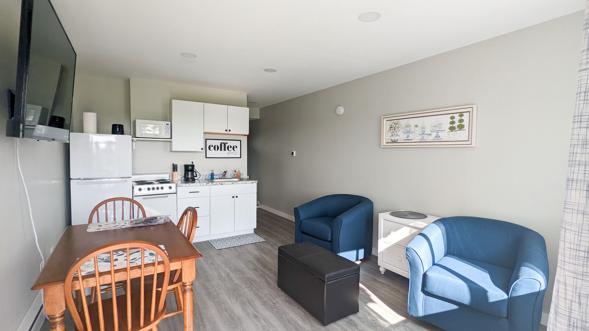A living room with a table , chairs , and a flat screen tv.