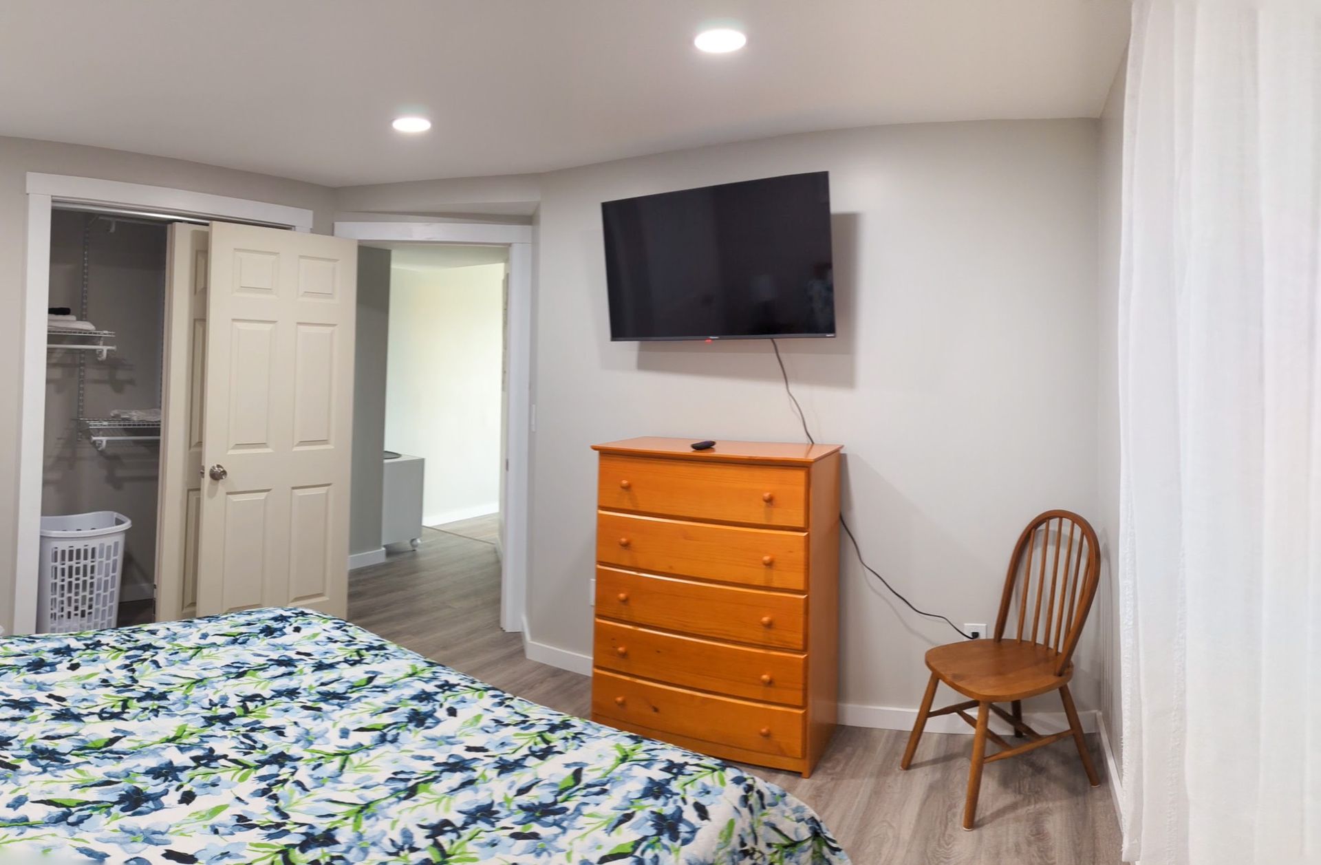 A bedroom with a bed , dresser , chair and television.