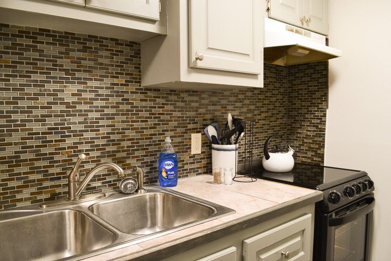 A kitchen with a sink a stove and a kettle
