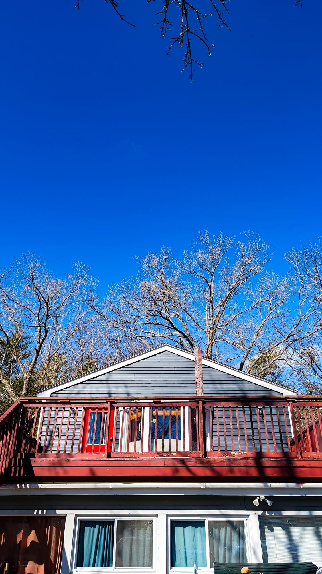 A house with a red deck and a blue sky in the background.