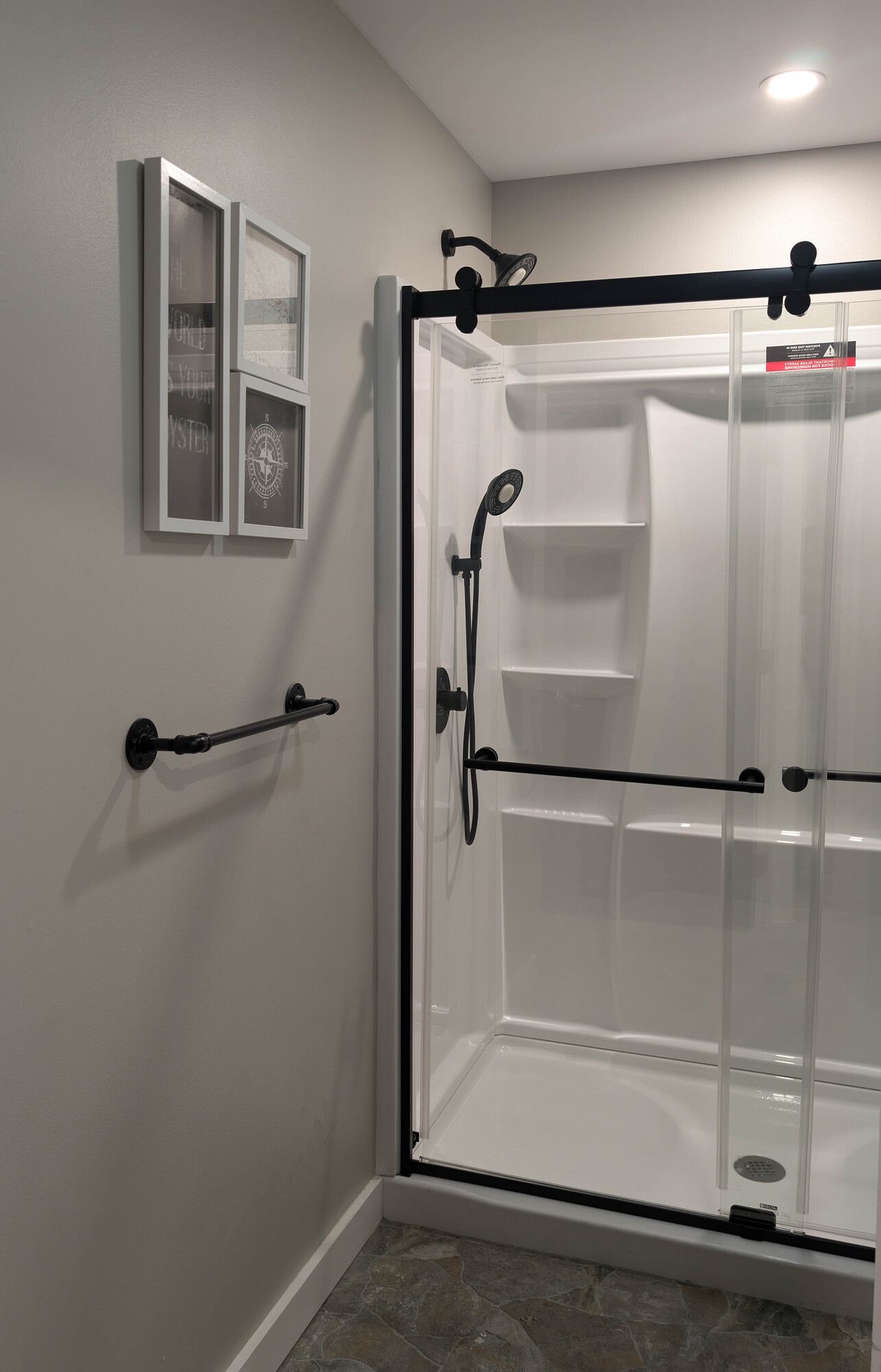 A bathroom with a sliding glass shower door and a window.