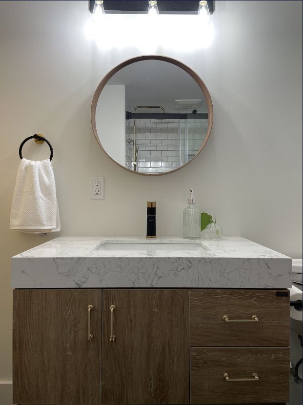 A bathroom sink with a round mirror above it.