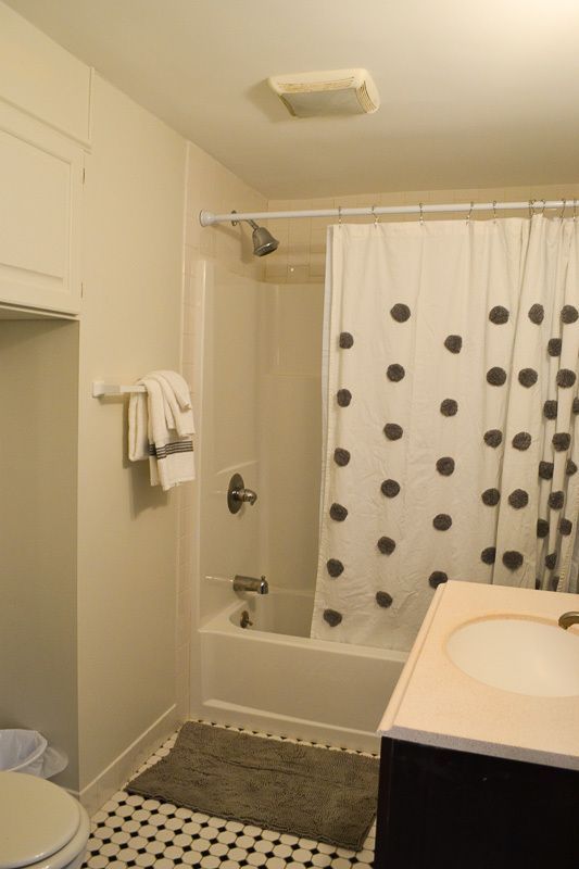 A bathroom with a white shower curtain with black polka dots