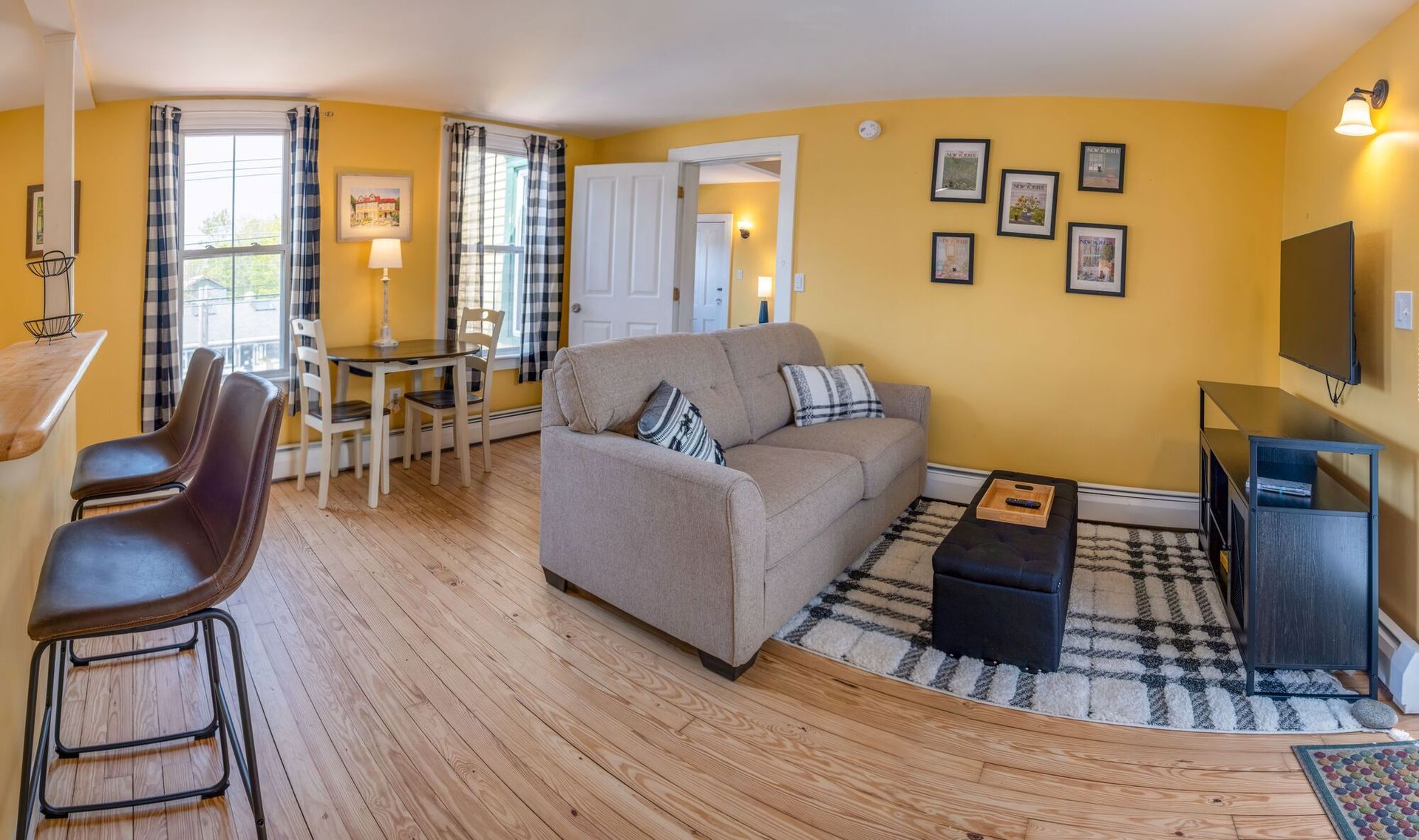 A living room with a couch , table , chairs and a flat screen tv.