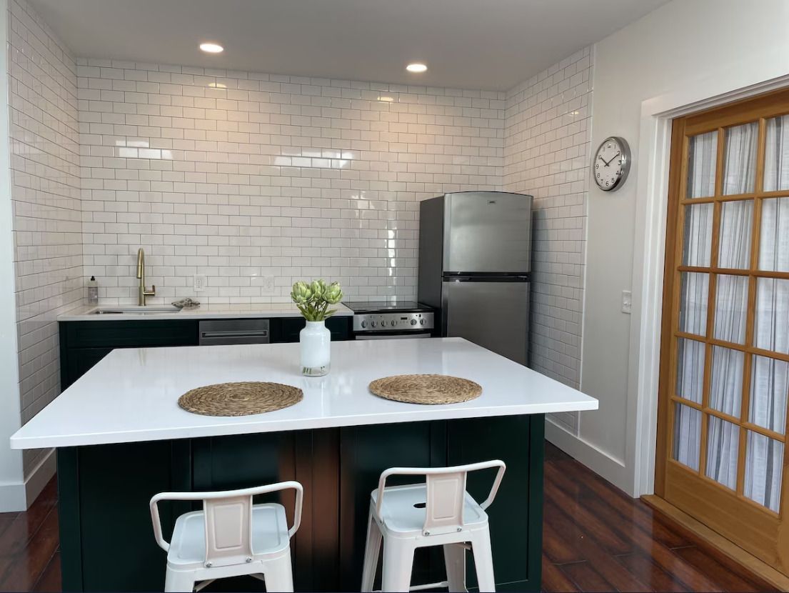 A kitchen with a large island and a couch in the background.