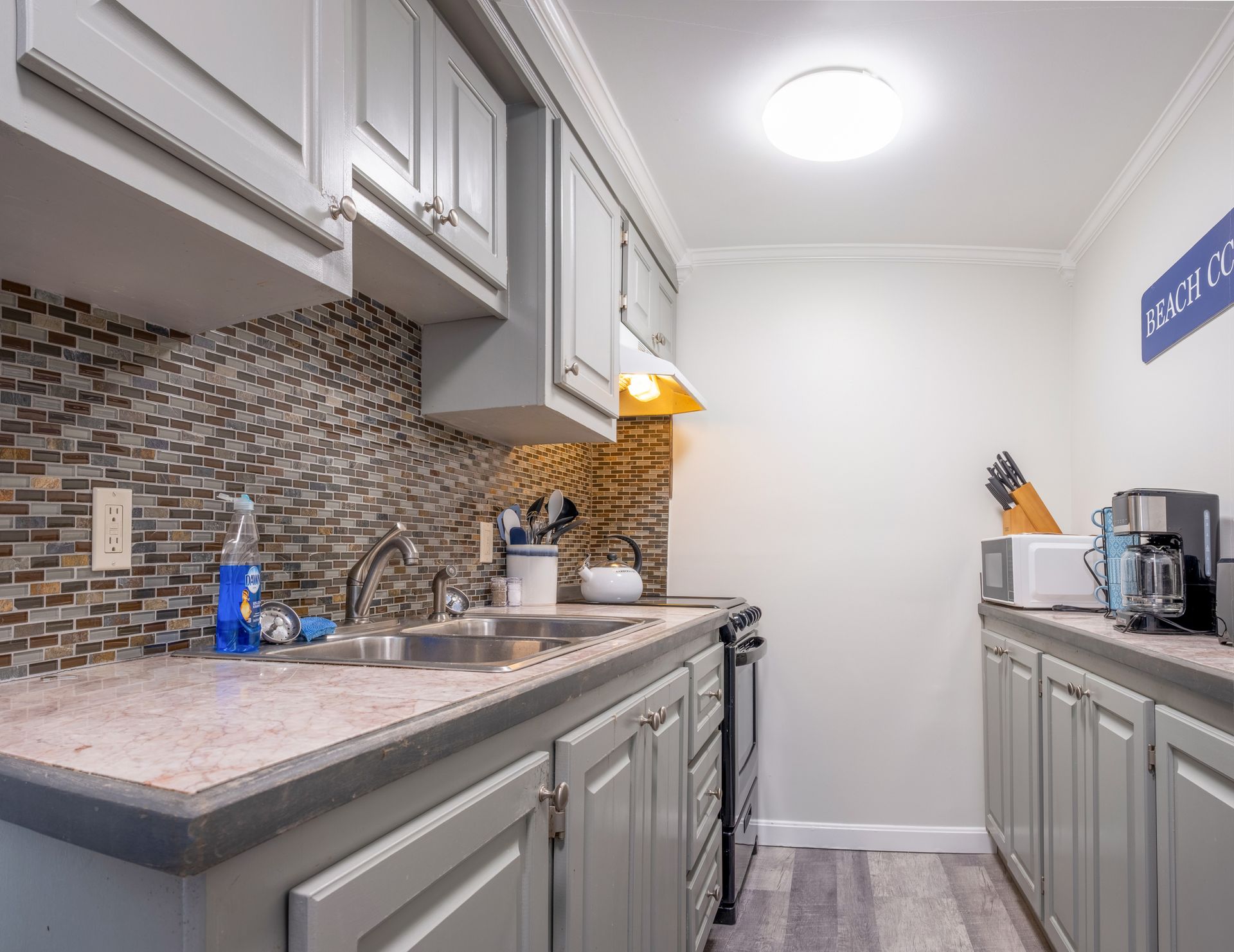 A kitchen with a sink , stove and microwave