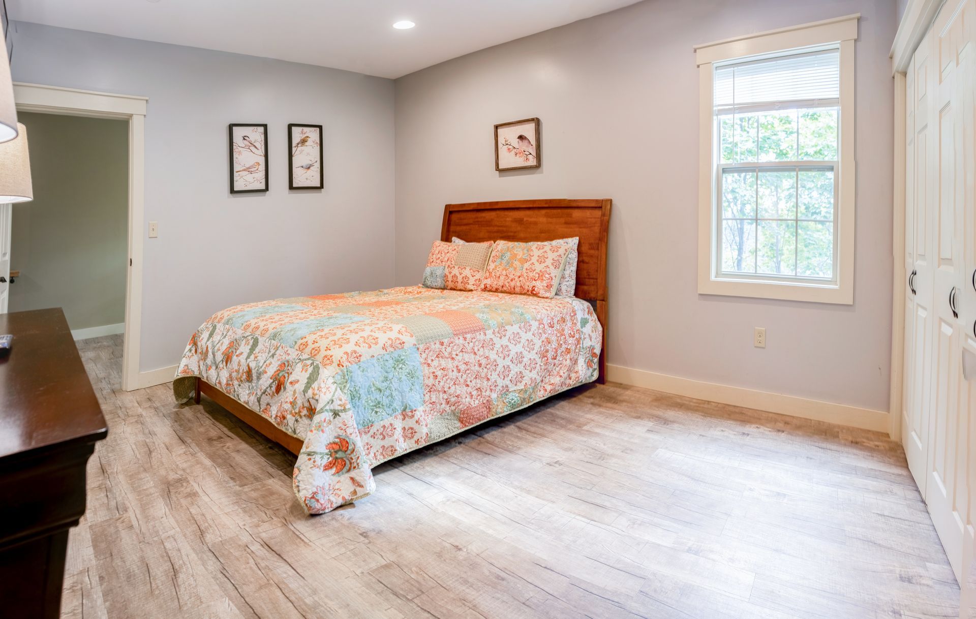 A bedroom with a bed , dresser , and window.
