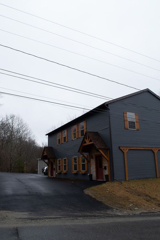 A gray house with a lot of windows and a car parked in front of it