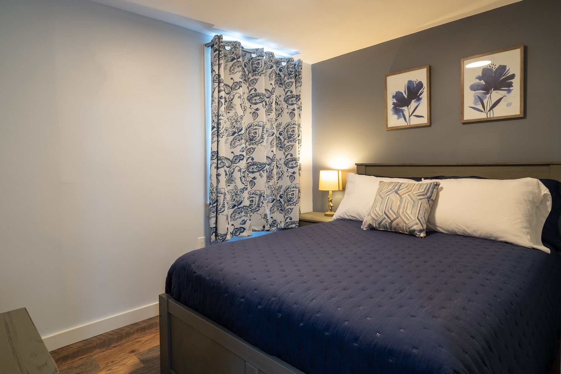 A bedroom with a king size bed and two pictures on the wall.
