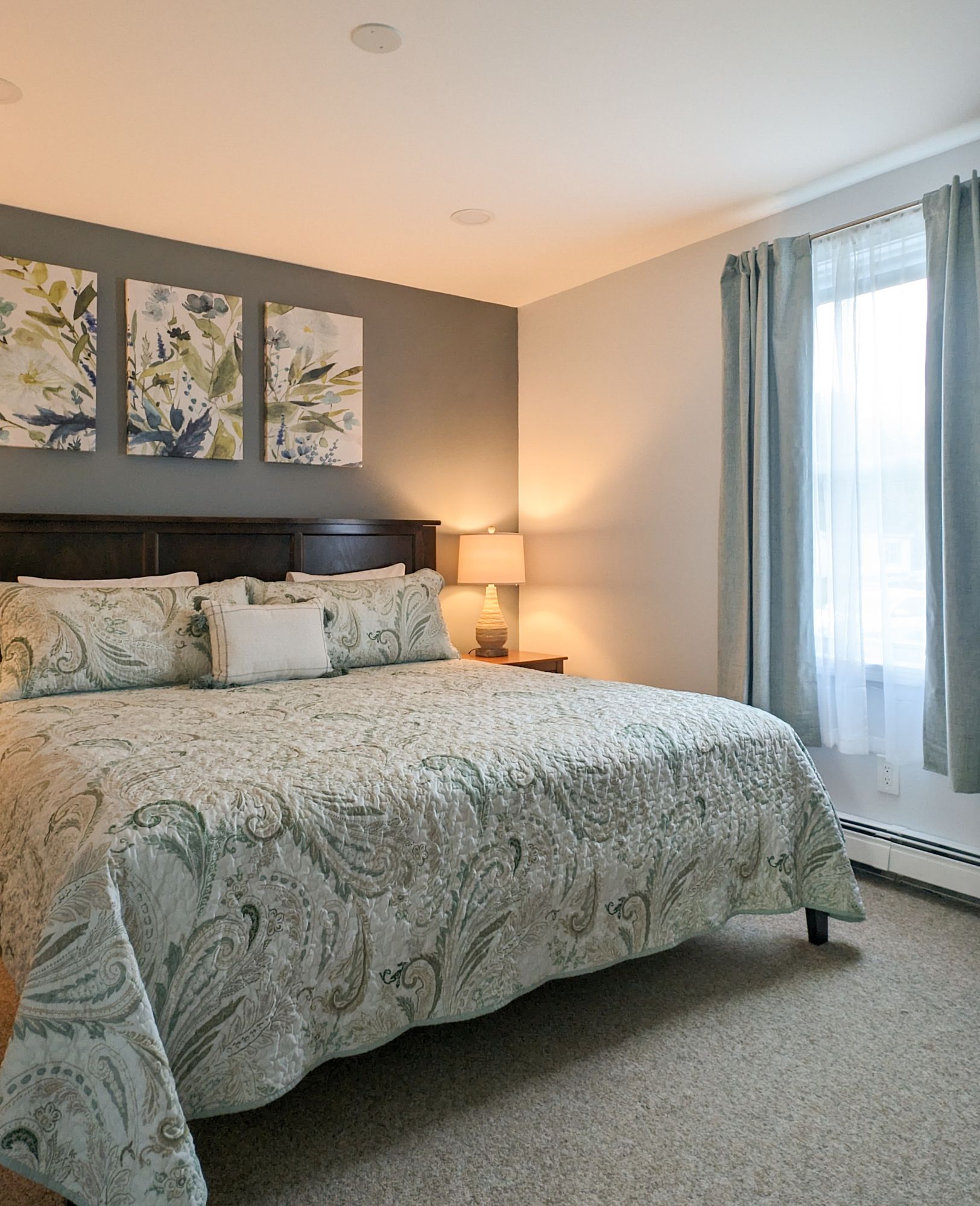 A bedroom with a large bed and three paintings on the wall