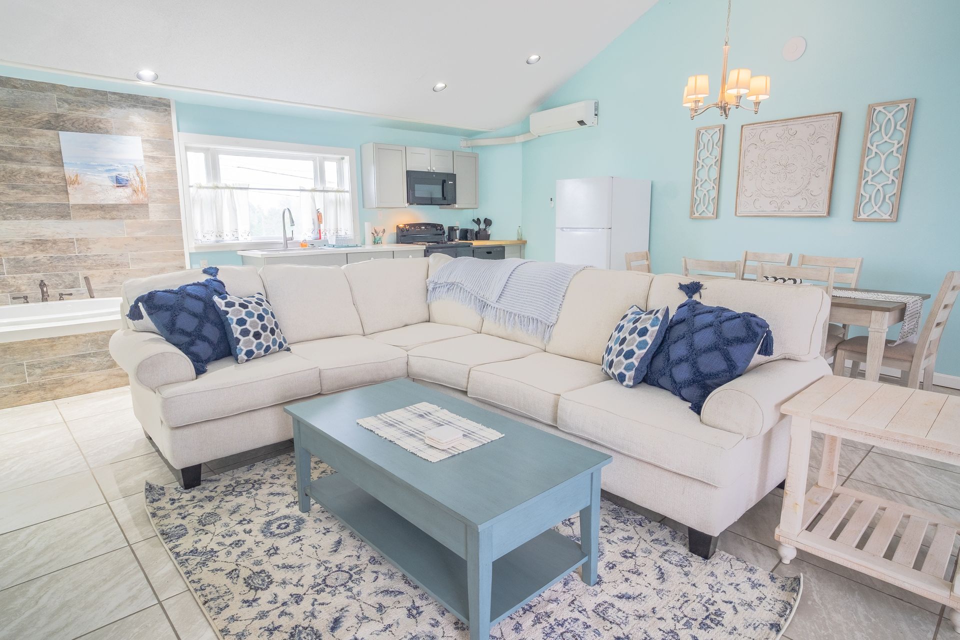 A living room with a white sectional couch and a blue coffee table.