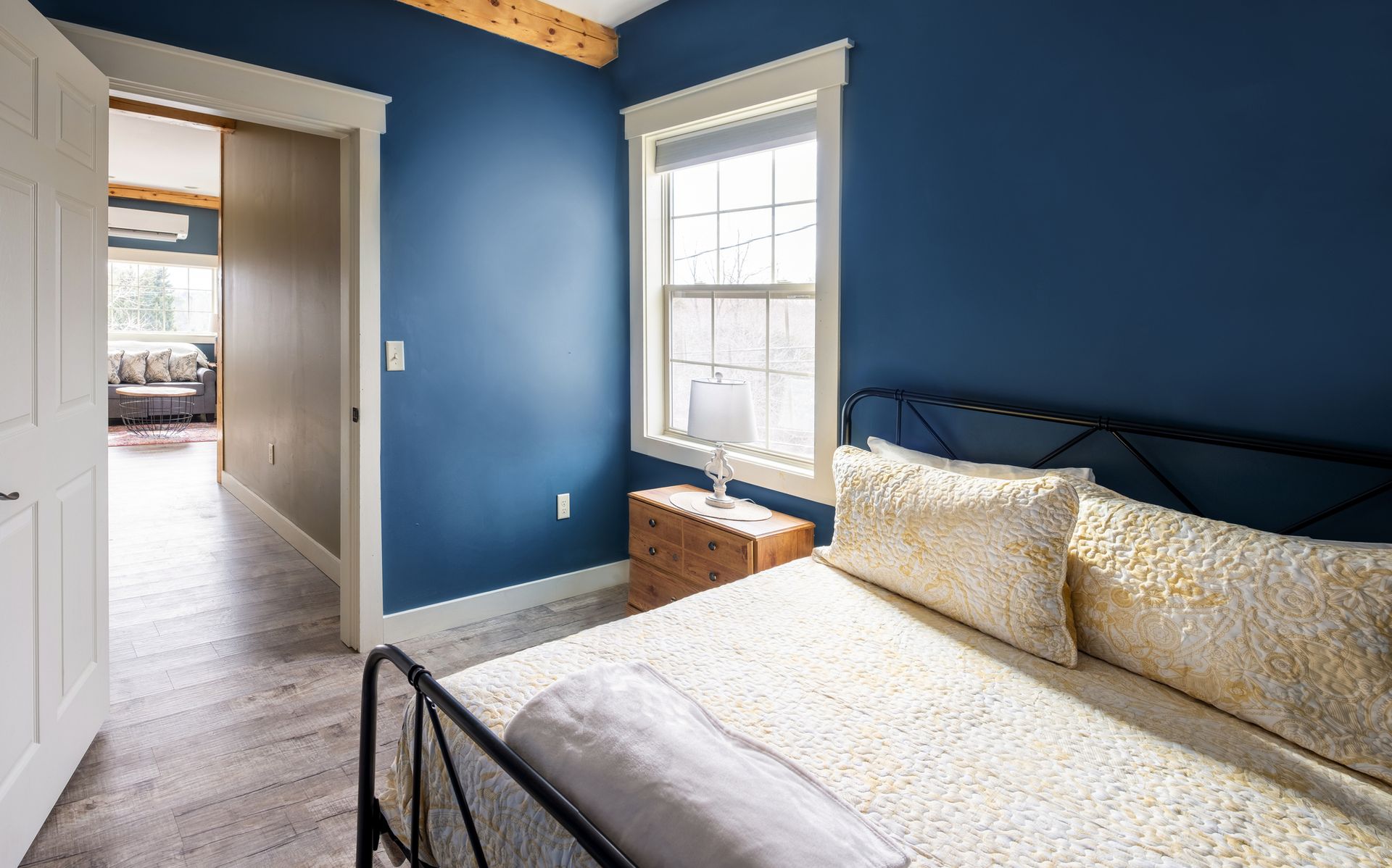 A bedroom with blue walls , a bed , a nightstand and a window.