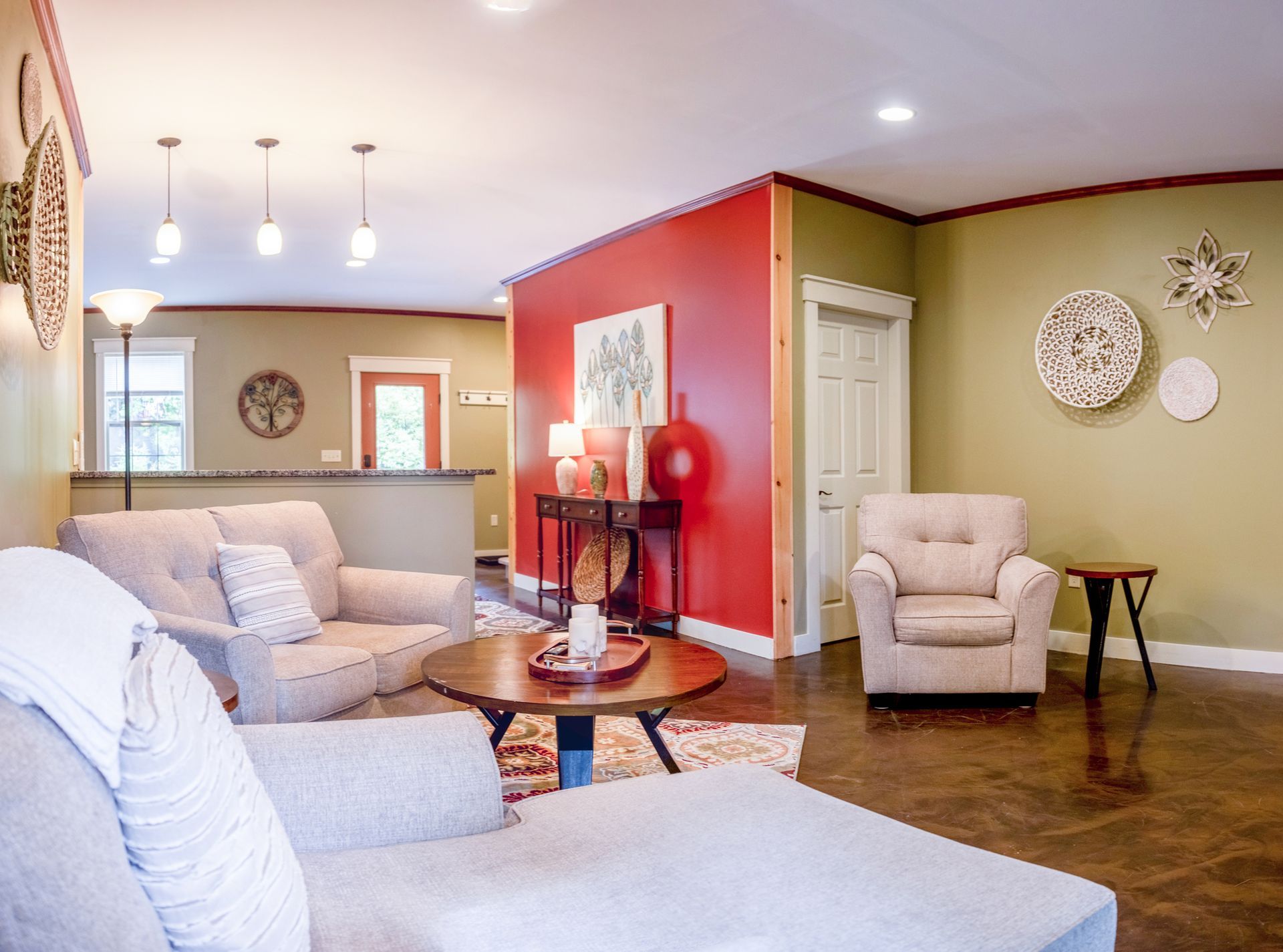 A living room with a couch , chairs , a table and a red wall.