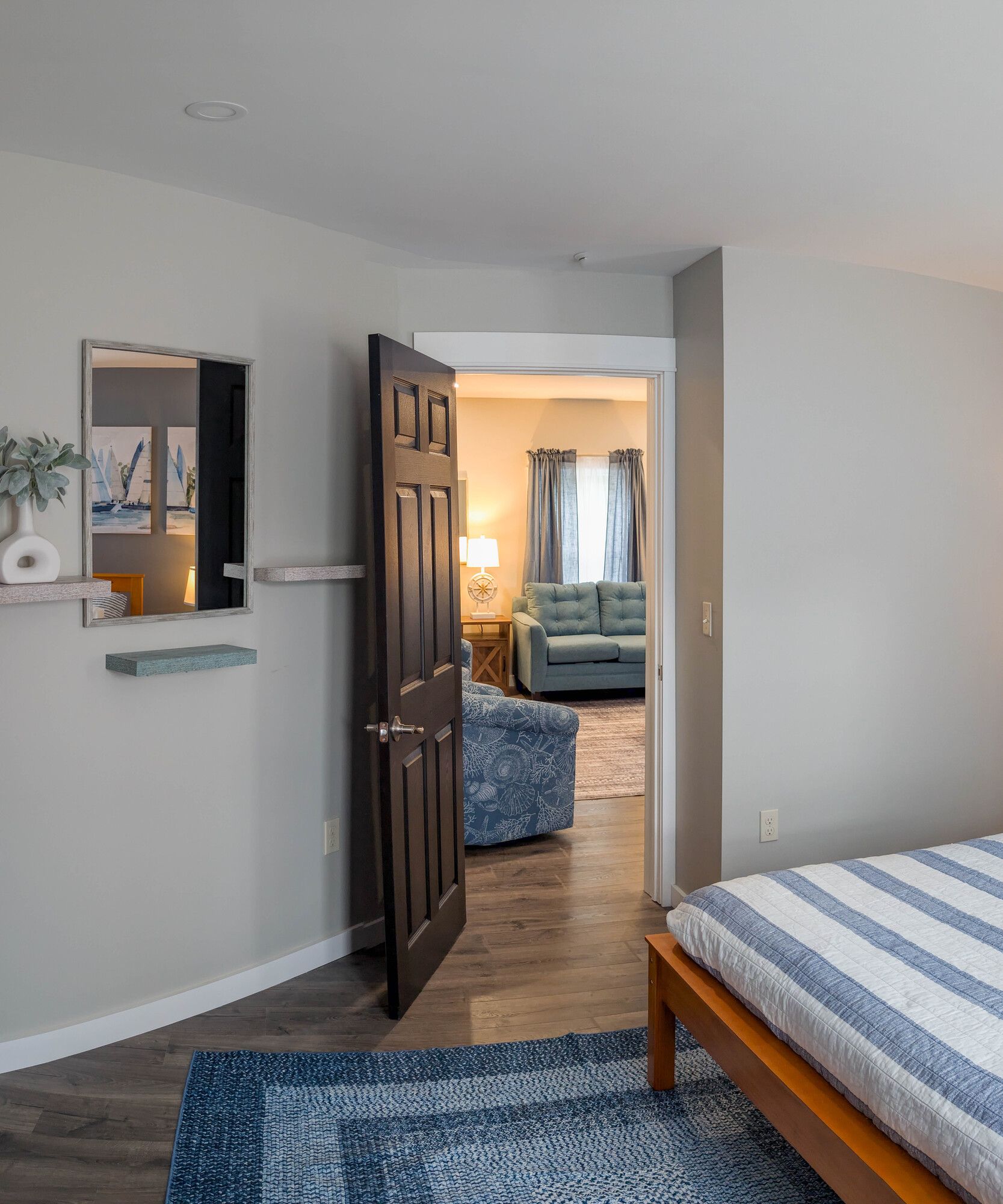 A bedroom with a bed , rug , mirror and couch.