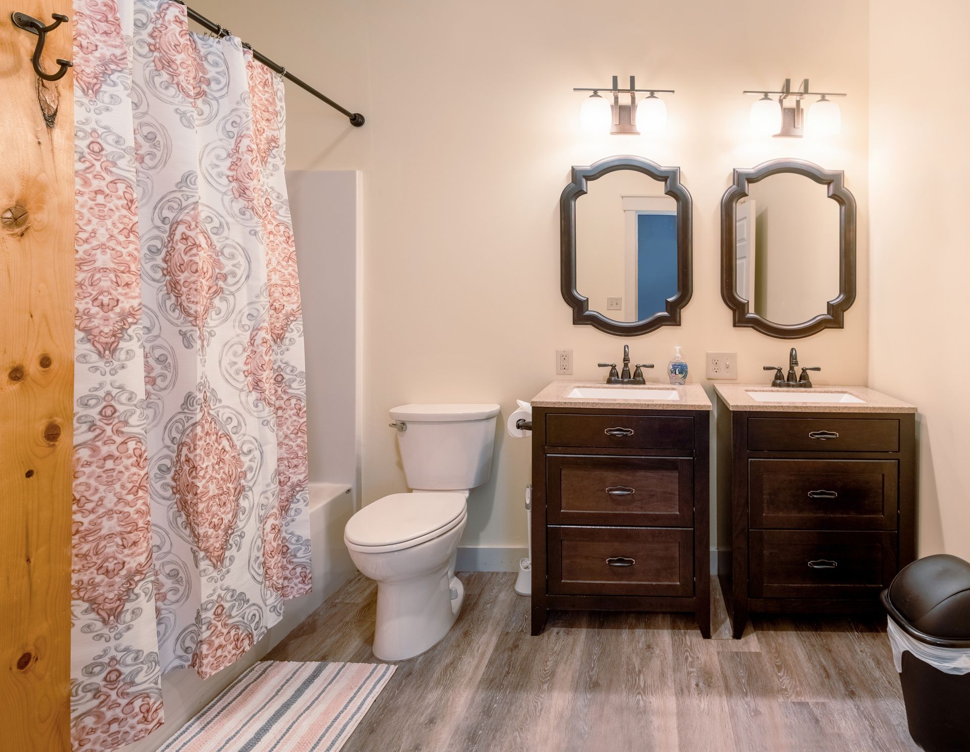 A bathroom with two sinks , a toilet , and a shower curtain.