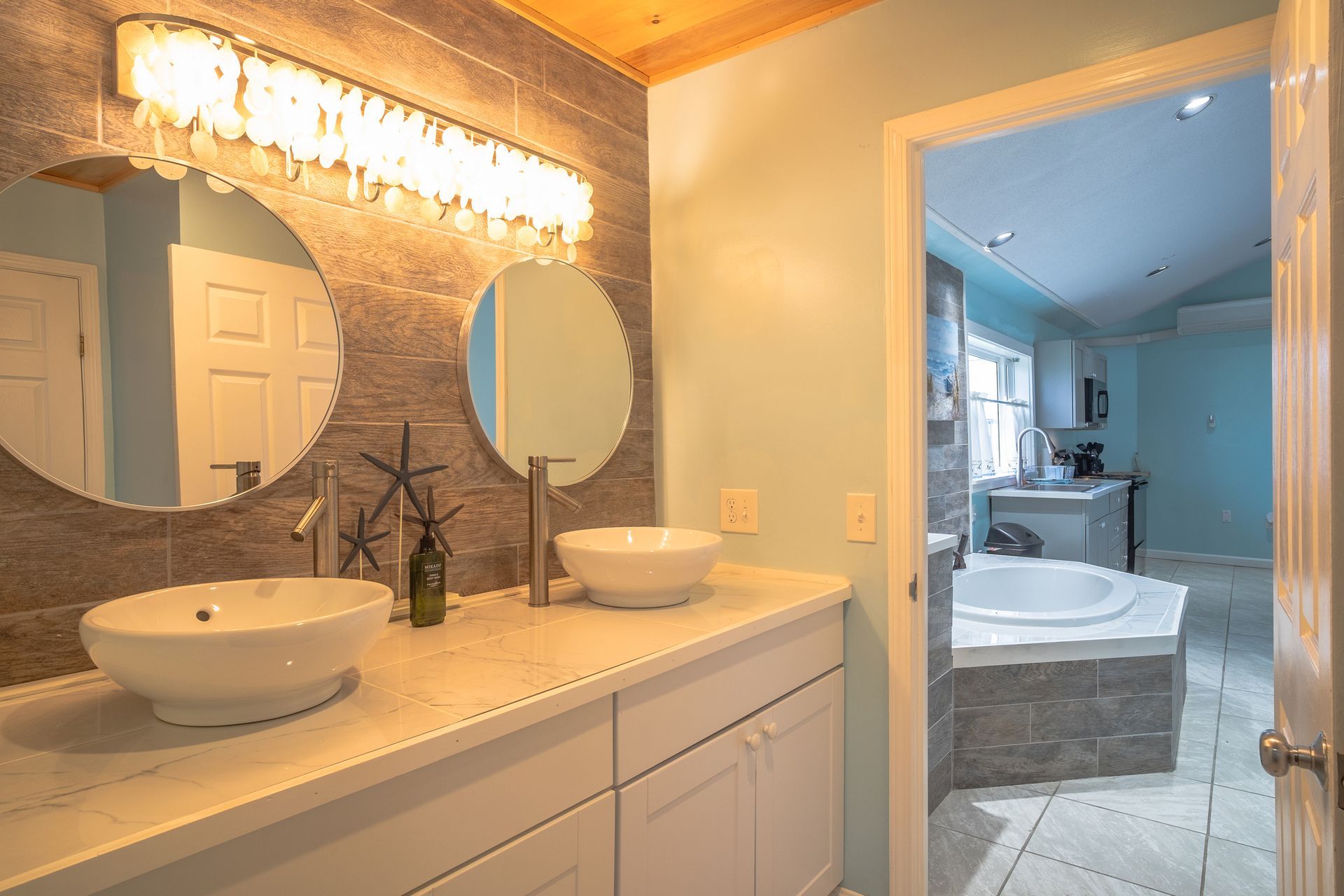 A bathroom with two sinks , two mirrors and a tub.