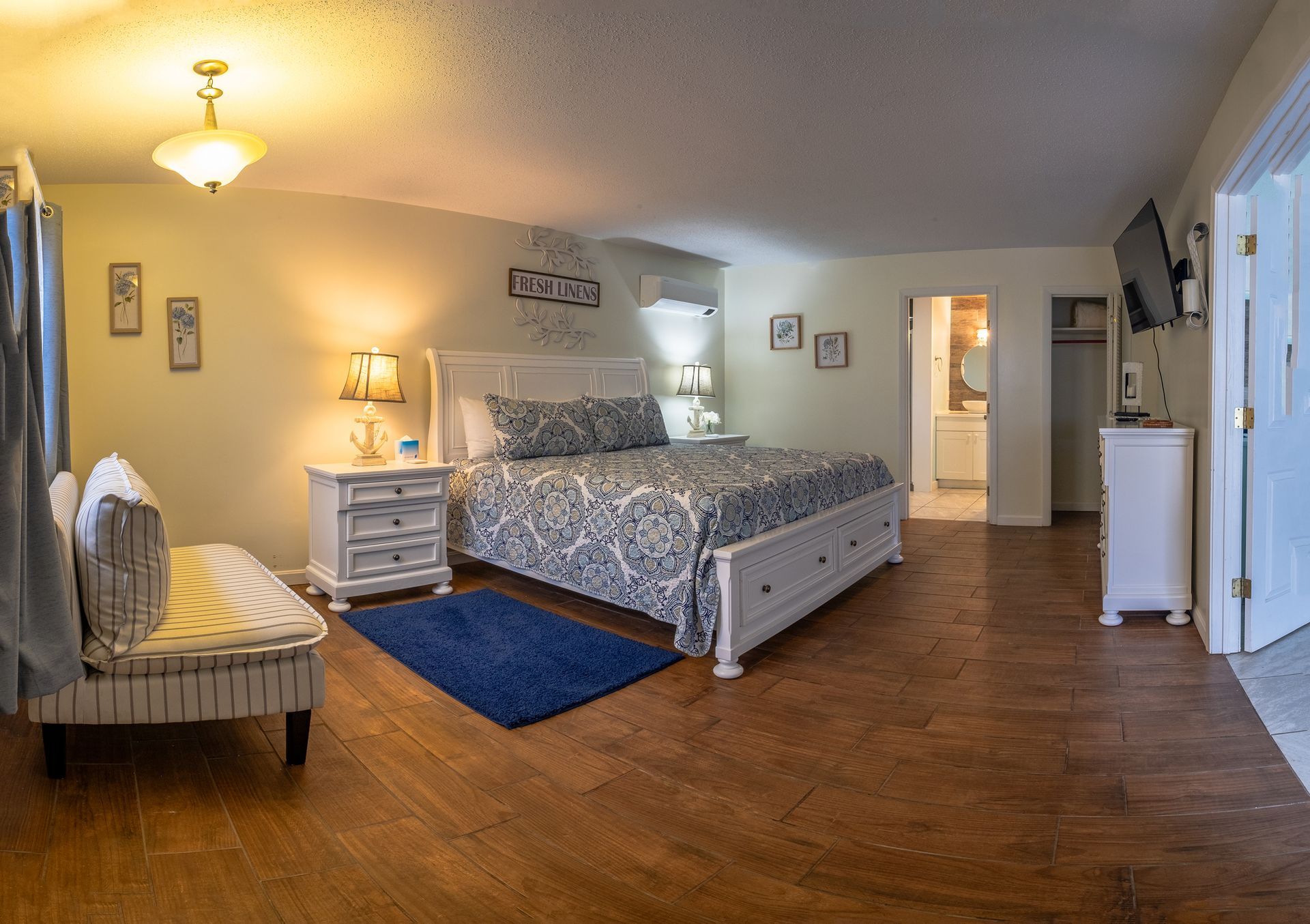 A bedroom with a king size bed , dresser , nightstand , and television.