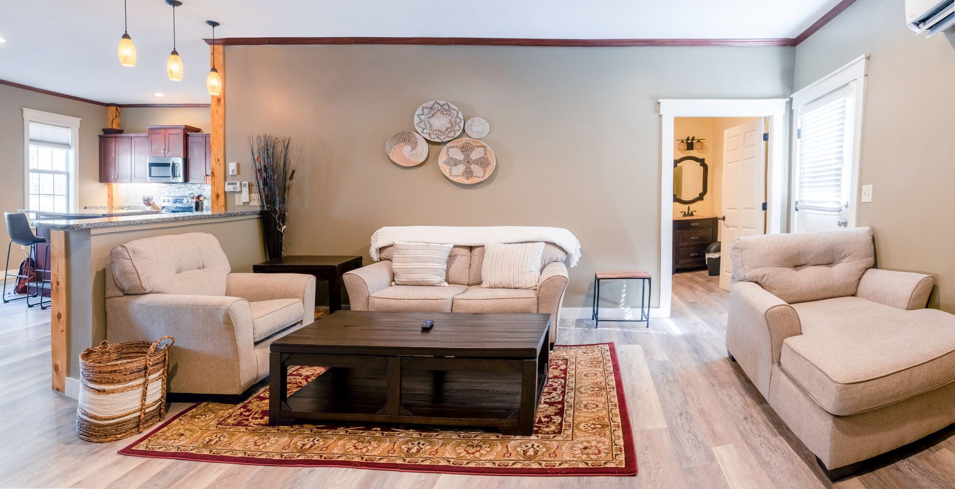 A living room with a couch , chairs , coffee table and rug.