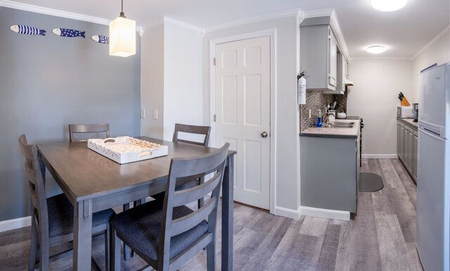 A dining room table and chairs in a kitchen with a refrigerator.