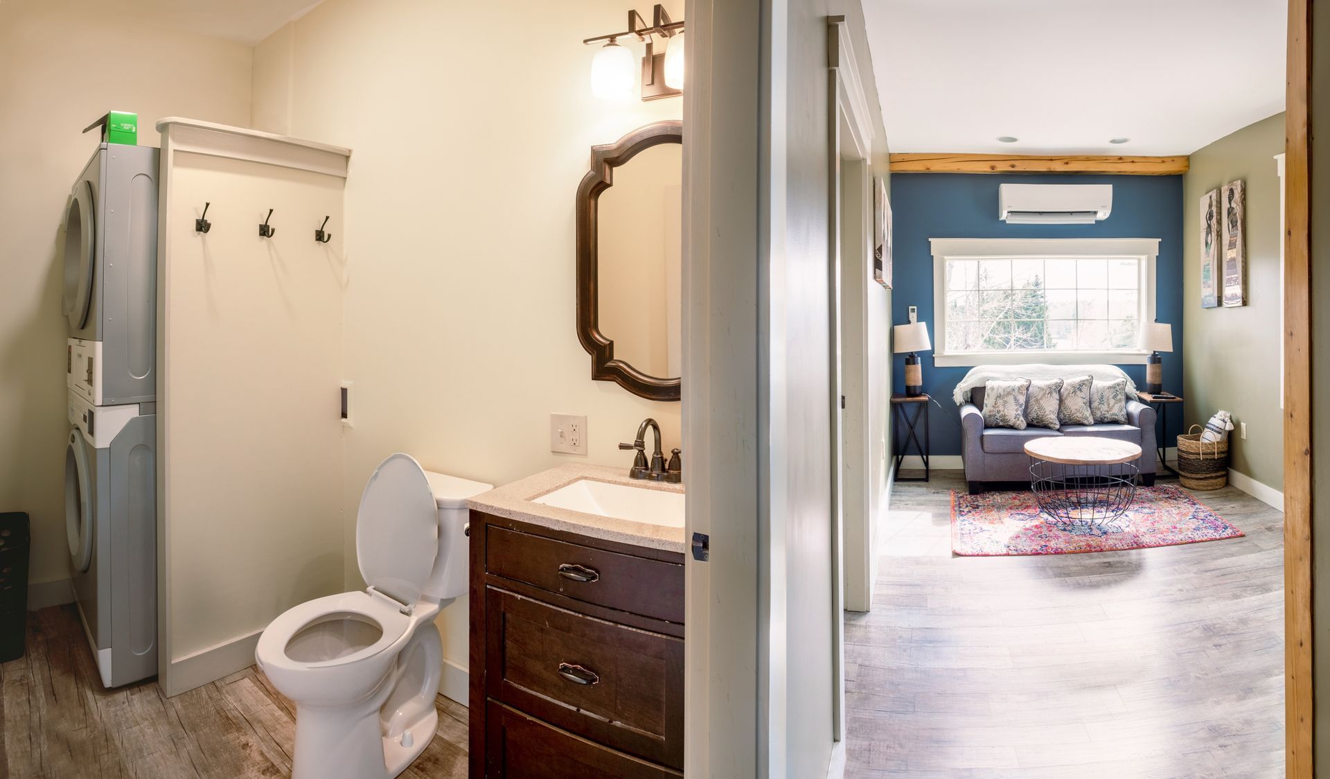 A bathroom with a toilet , sink and mirror next to a living room.