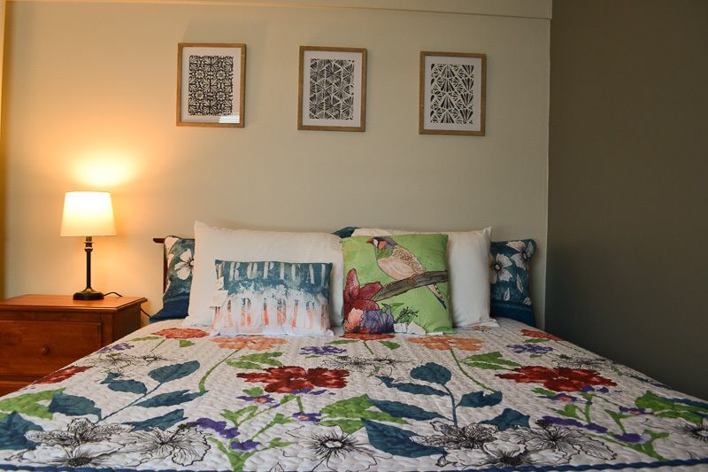 A bed with a floral comforter and pillows in a bedroom.