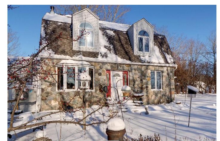 A large stone house covered in snow with a red door
