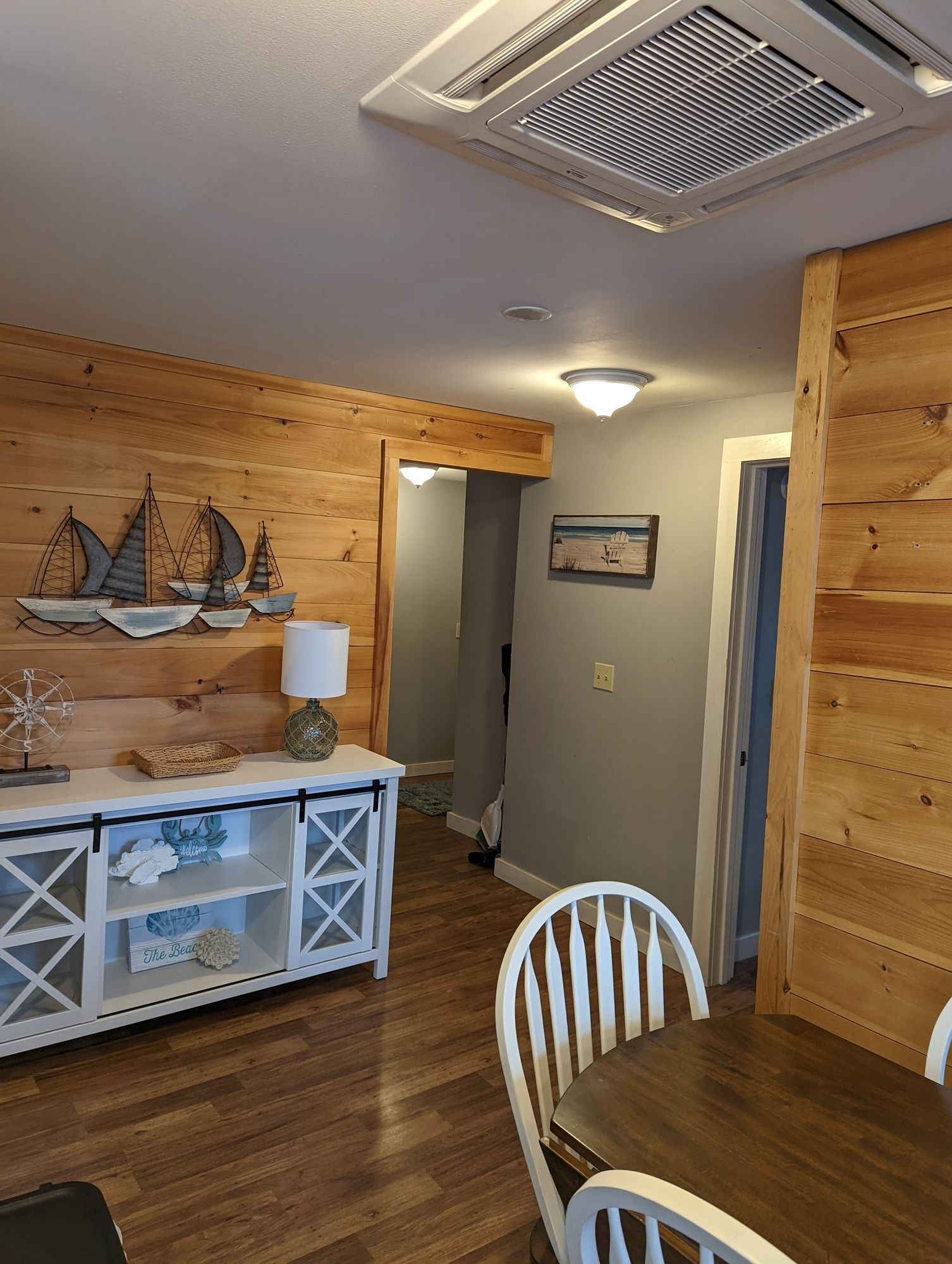 A living room with wooden walls and a table and chairs.