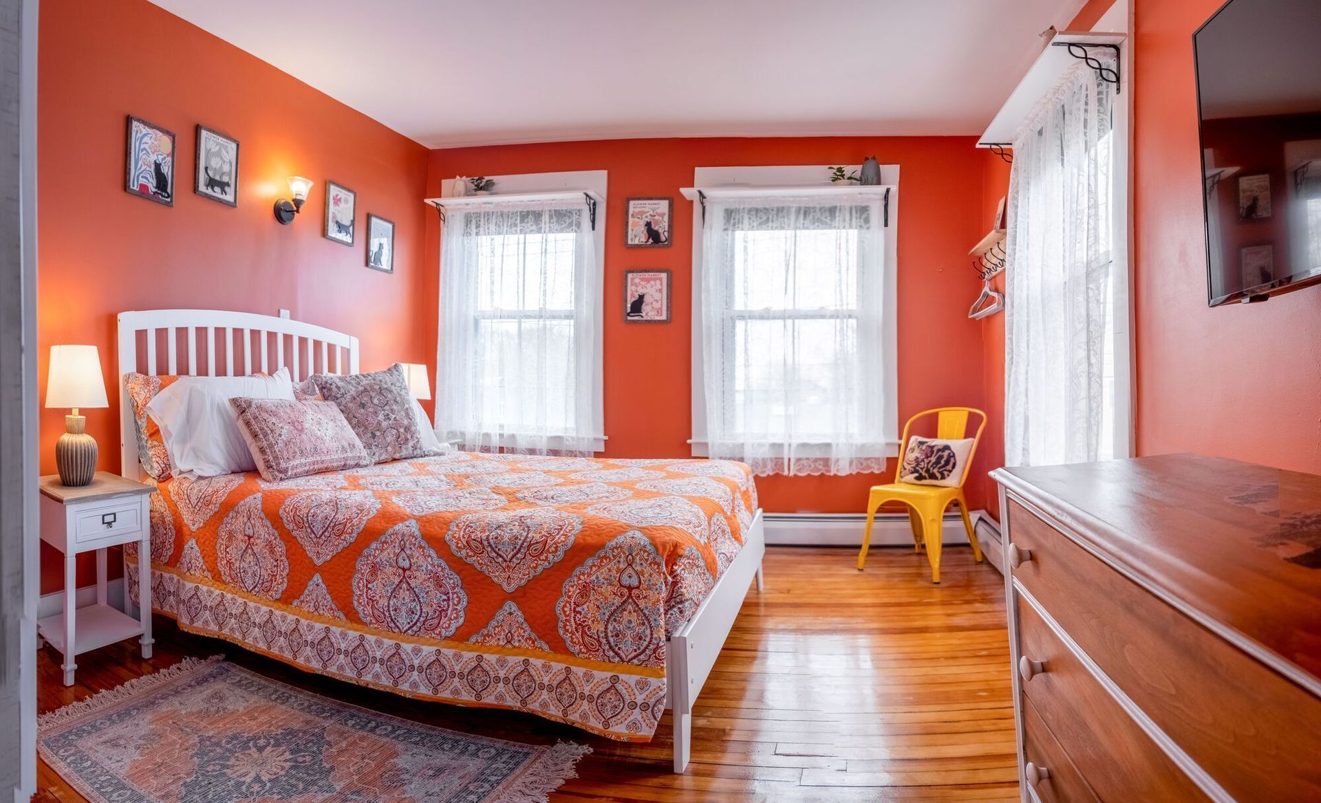 A bedroom with orange walls and a king size bed