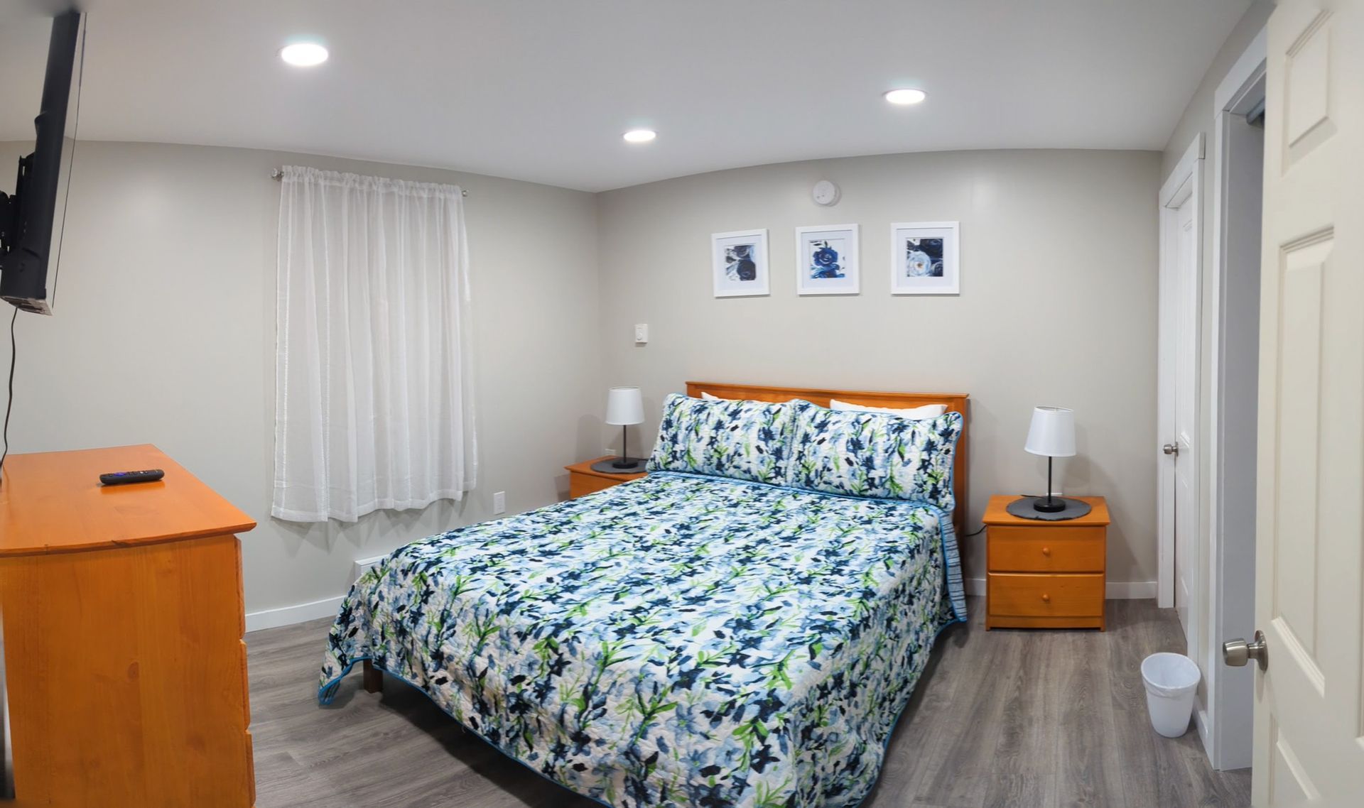 A bedroom with a bed , dresser , nightstand and television.