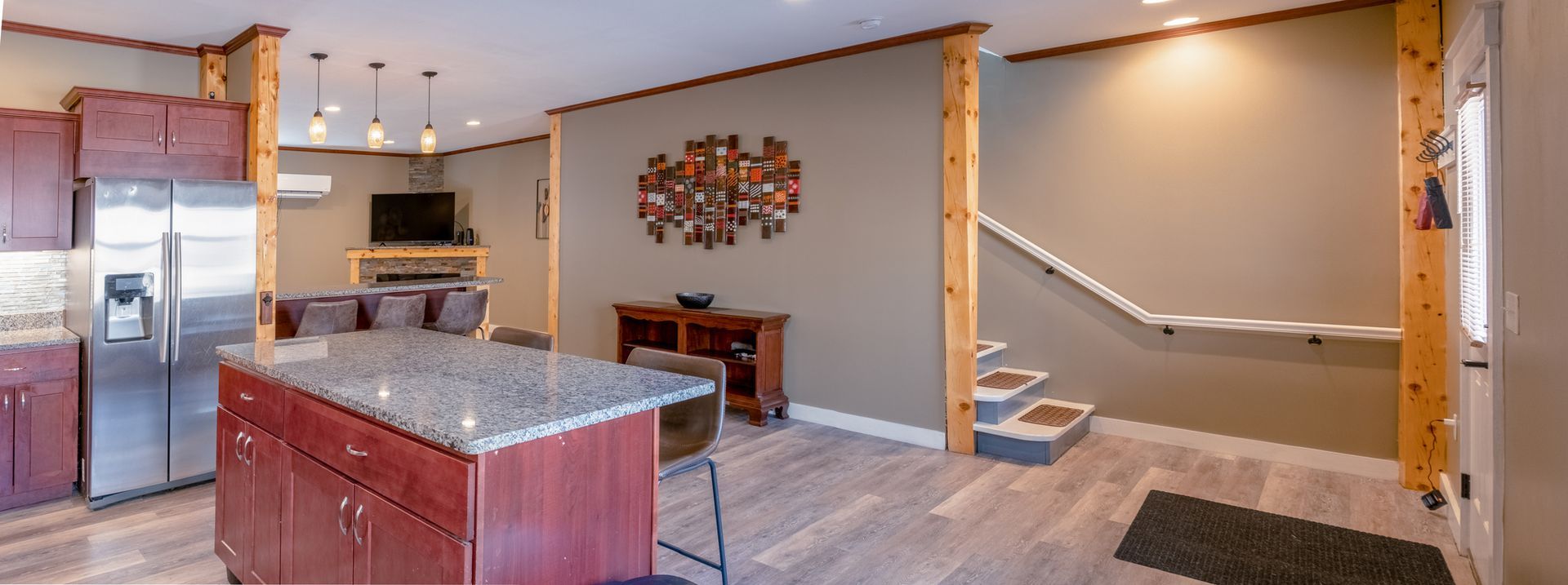 A kitchen with stainless steel appliances , granite counter tops , red cabinets and a large island.