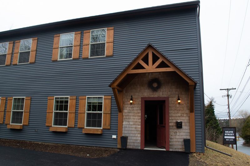 A gray building with a red door and shutters
