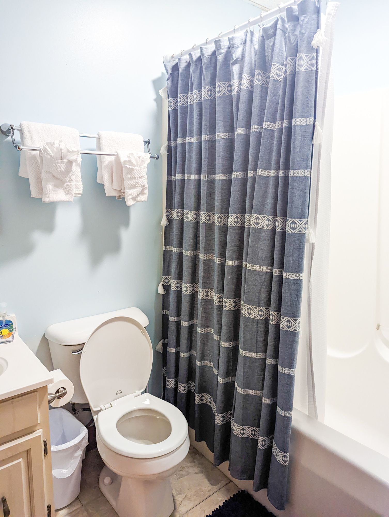A bathroom with a toilet , sink , and shower curtain.