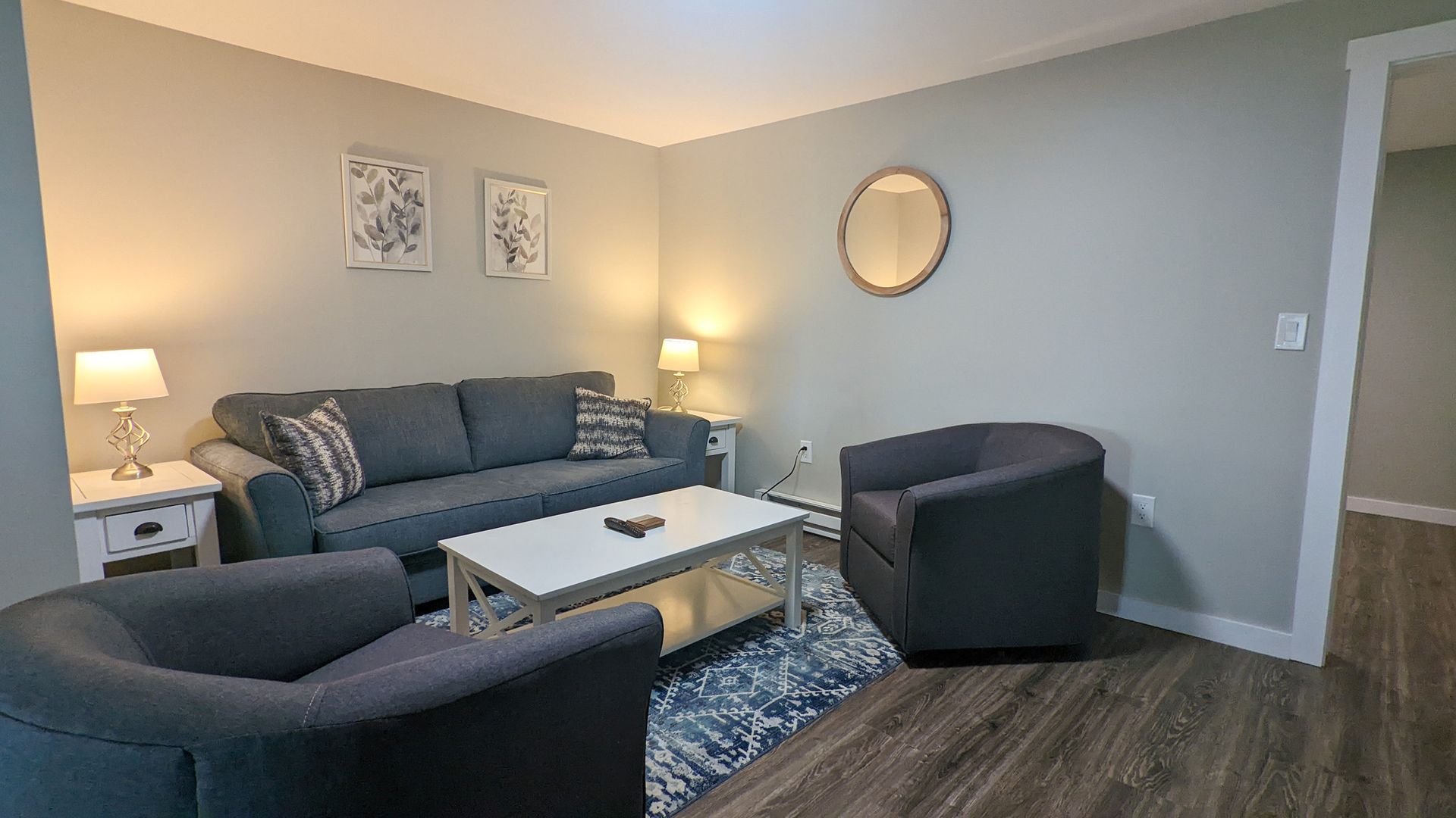 A living room with a couch , two chairs , a coffee table and a mirror.