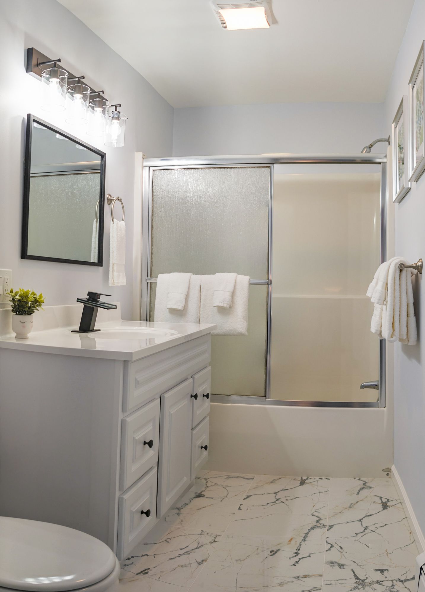 A bathroom with a toilet , sink , mirror and shower.