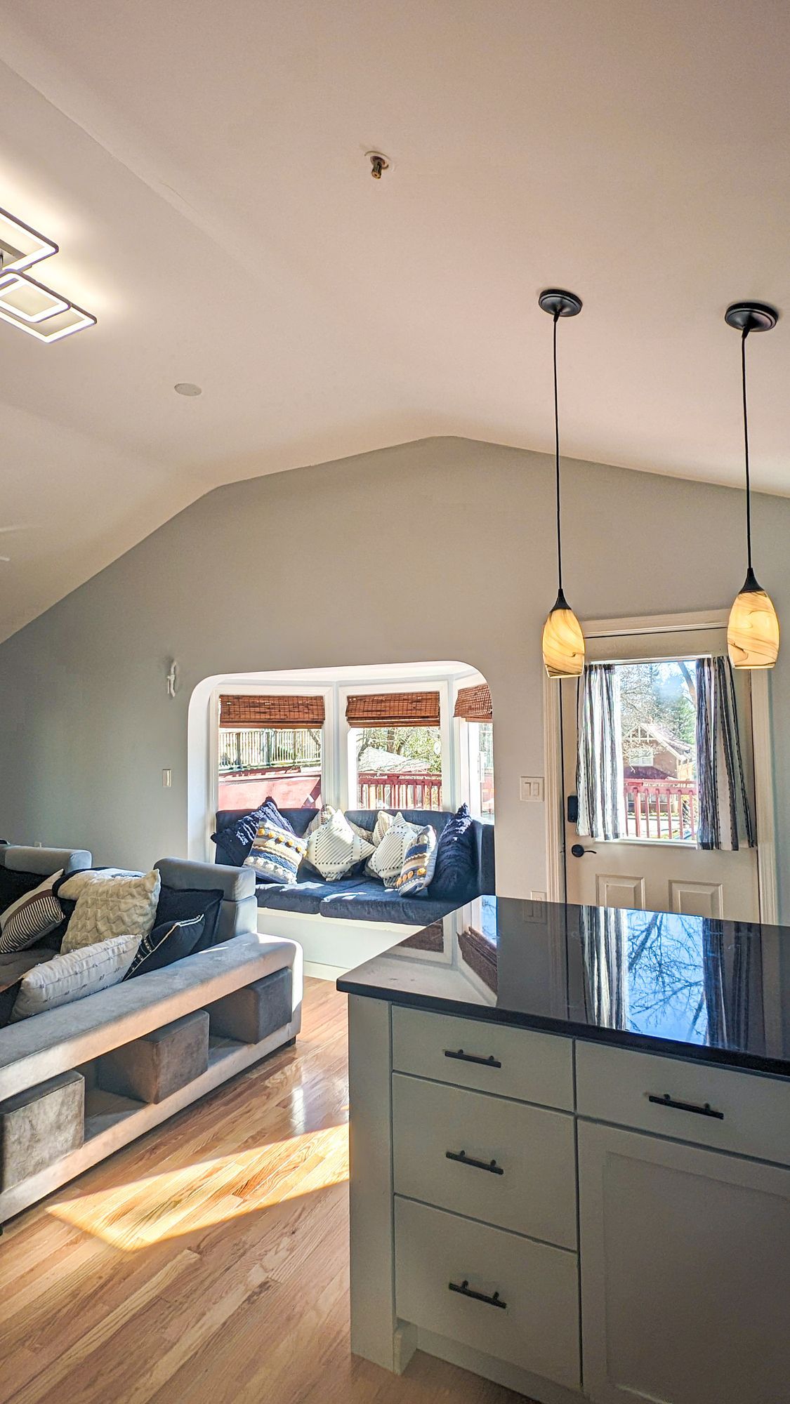 A kitchen with a large island and a couch in the background.