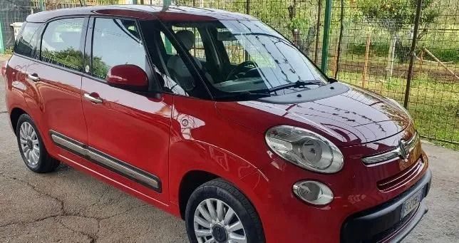 Un'auto rossa è parcheggiata davanti a una recinzione.